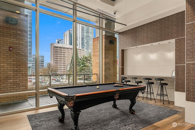 recreation room with hardwood / wood-style floors, expansive windows, a high ceiling, and billiards