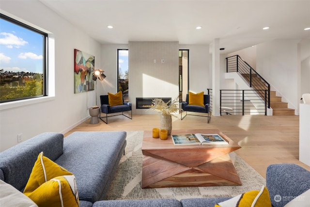 living room with a wealth of natural light, a fireplace, and light wood-type flooring