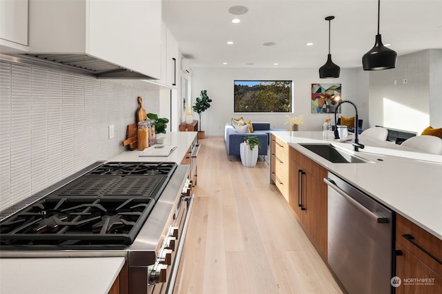 kitchen with sink, custom exhaust hood, white cabinetry, hanging light fixtures, and appliances with stainless steel finishes