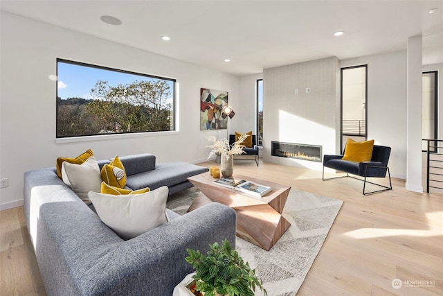 living room with a healthy amount of sunlight, a large fireplace, and light hardwood / wood-style flooring