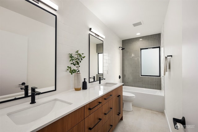 full bathroom featuring vanity, a healthy amount of sunlight, tiled shower / bath combo, and toilet