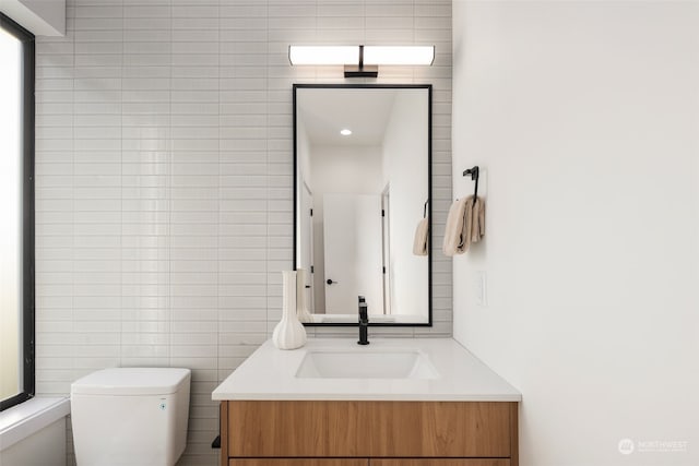 bathroom with vanity, toilet, and tile walls