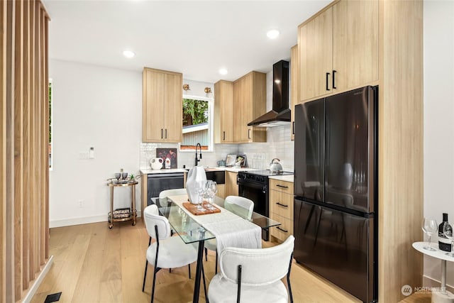 kitchen featuring black appliances, light hardwood / wood-style flooring, light brown cabinets, wall chimney range hood, and backsplash