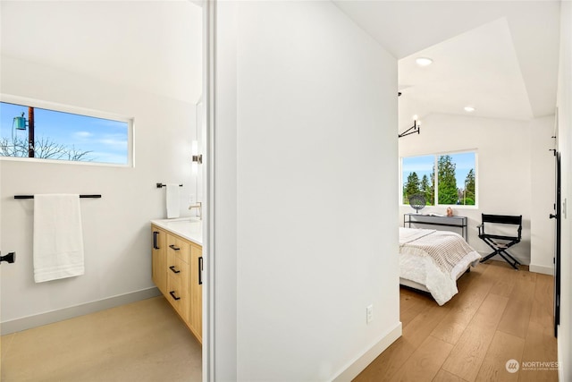 bathroom featuring hardwood / wood-style flooring, vaulted ceiling, and vanity