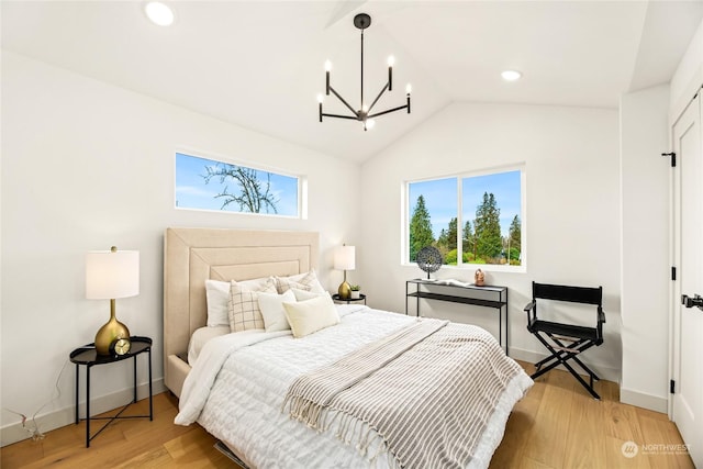 bedroom featuring multiple windows, vaulted ceiling, an inviting chandelier, and light hardwood / wood-style flooring