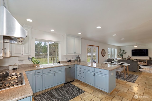 kitchen with sink, stainless steel appliances, wall chimney range hood, kitchen peninsula, and white cabinets