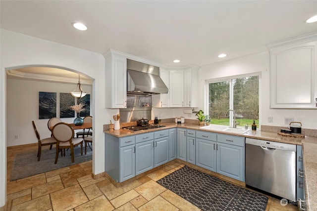 kitchen with sink, wall chimney exhaust hood, decorative light fixtures, white cabinets, and appliances with stainless steel finishes