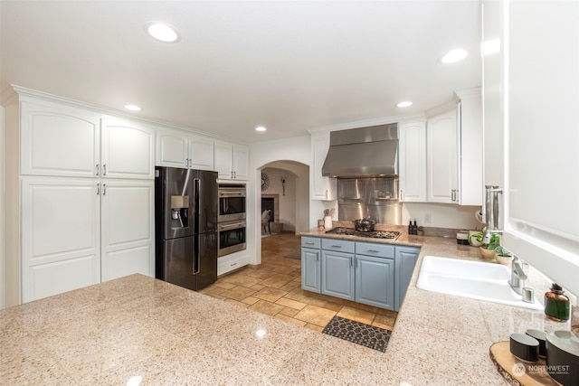 kitchen featuring white cabinetry, stainless steel appliances, and wall chimney range hood