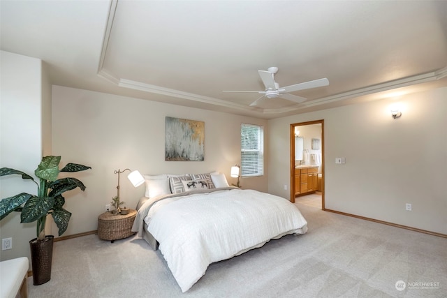 carpeted bedroom featuring a tray ceiling, ensuite bath, and ceiling fan