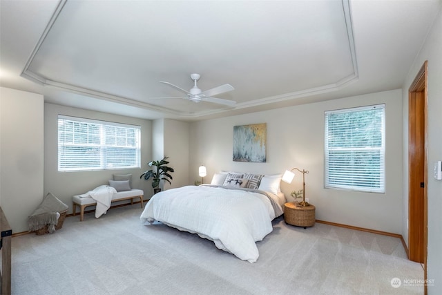 carpeted bedroom with ceiling fan and a tray ceiling