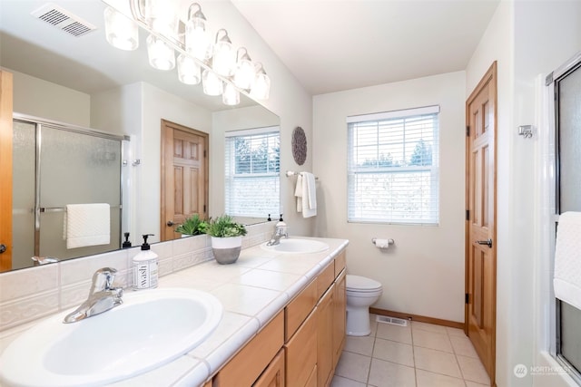 bathroom featuring toilet, vanity, tile patterned floors, and a shower with door