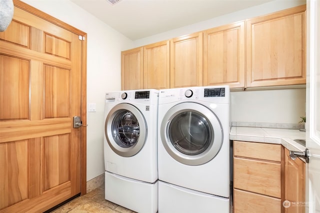 washroom with washer and clothes dryer and cabinets