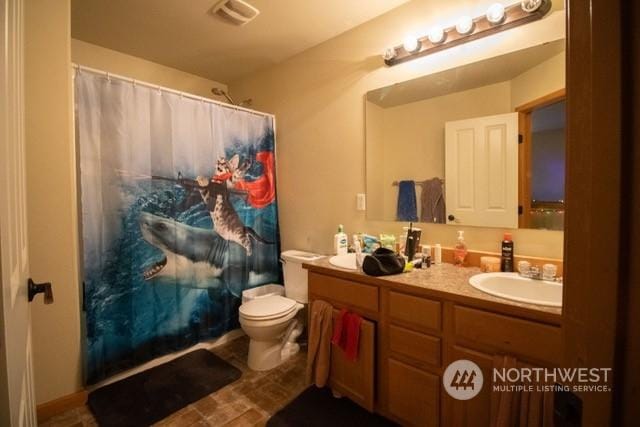 bathroom featuring vanity, curtained shower, and toilet