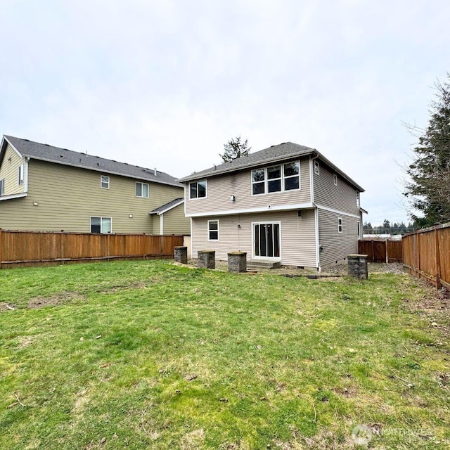 rear view of property featuring a lawn and a fenced backyard