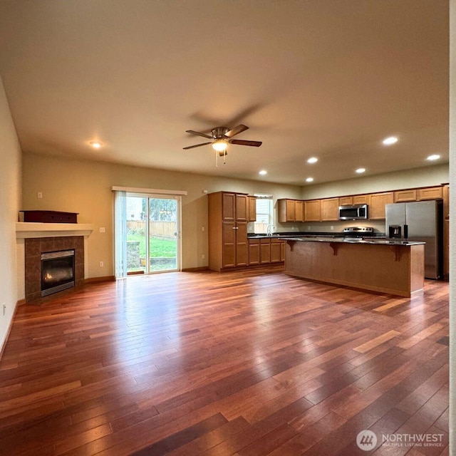 unfurnished living room featuring dark wood-type flooring, a ceiling fan, recessed lighting, a fireplace, and baseboards