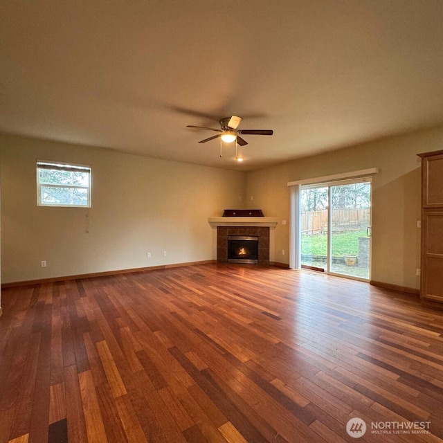 unfurnished living room featuring ceiling fan, baseboards, wood finished floors, and a tiled fireplace