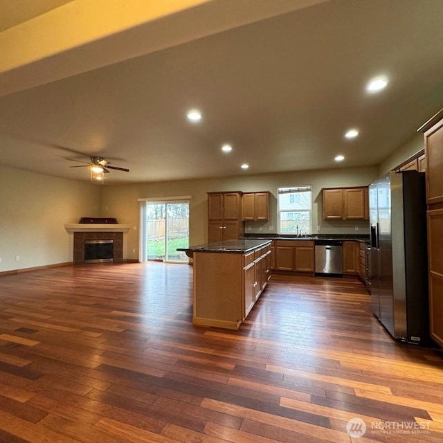 kitchen featuring dark wood finished floors, open floor plan, a fireplace, stainless steel appliances, and a sink