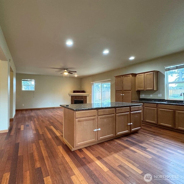 kitchen with a brick fireplace, baseboards, dark wood-style flooring, and a center island