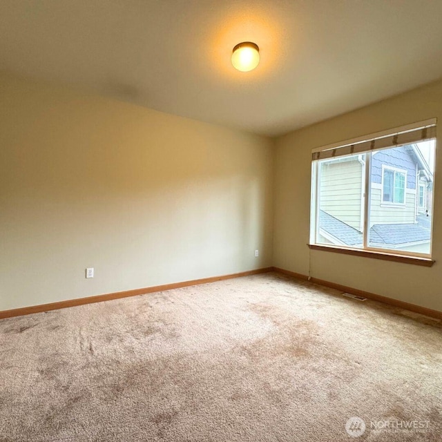 spare room with visible vents, light colored carpet, and baseboards