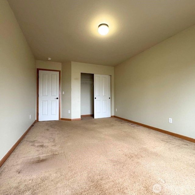 unfurnished bedroom featuring a closet, baseboards, and light colored carpet