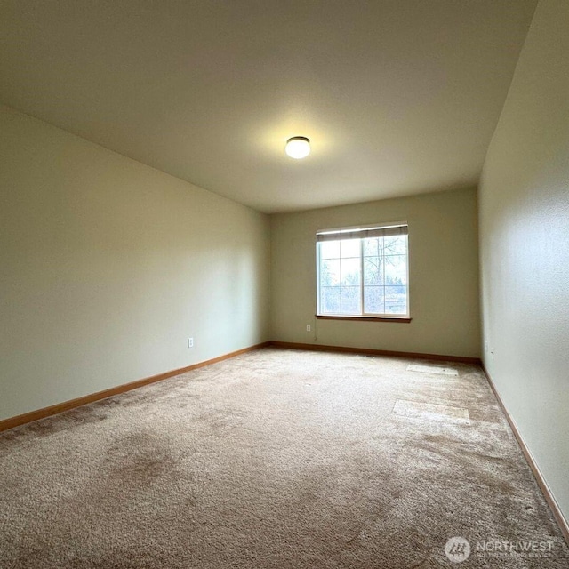 carpeted empty room featuring baseboards