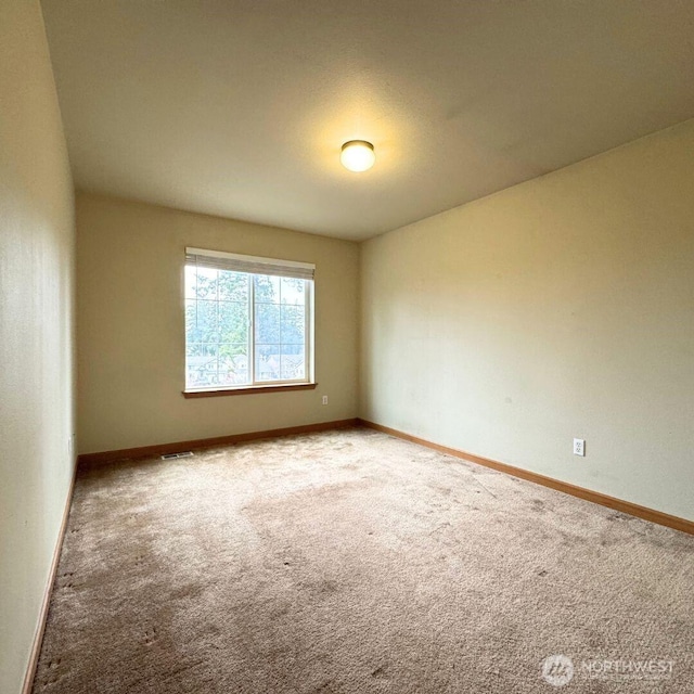 empty room with carpet flooring, visible vents, and baseboards