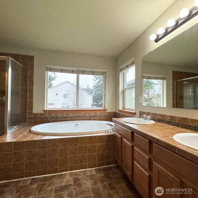 bathroom with a sink, a garden tub, double vanity, and a shower stall