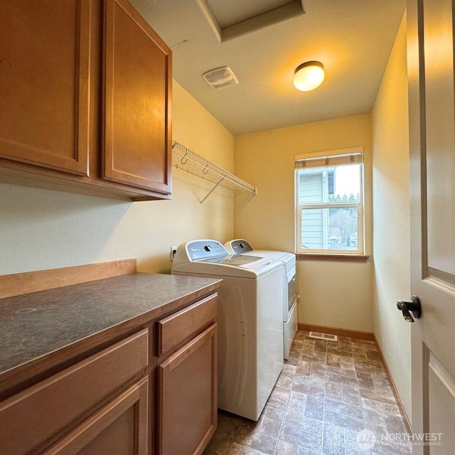 laundry room with washing machine and clothes dryer, visible vents, cabinet space, and baseboards