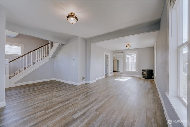 unfurnished living room featuring a wood stove and light wood-type flooring