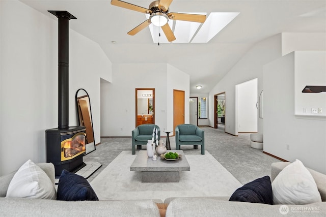 living room with baseboards, light colored carpet, ceiling fan, a wood stove, and high vaulted ceiling