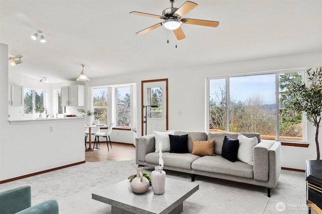 living room with light wood finished floors, ceiling fan, and baseboards