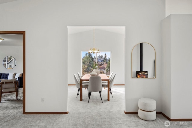 carpeted dining area with baseboards, lofted ceiling, and a notable chandelier