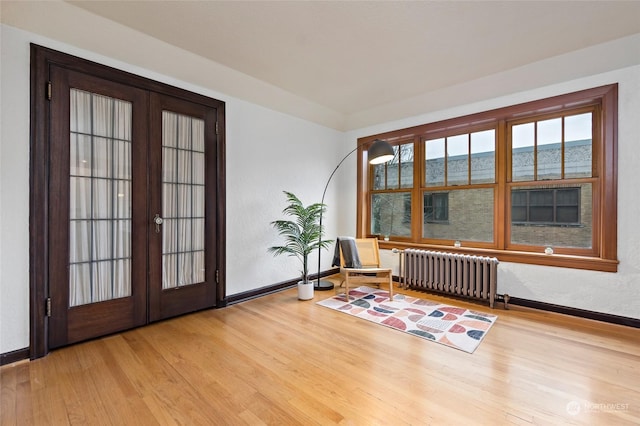 interior space with radiator heating unit, french doors, and light hardwood / wood-style flooring