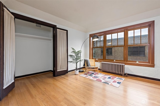 interior space with a closet, radiator heating unit, and light hardwood / wood-style flooring