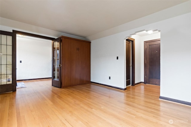 unfurnished room featuring french doors and light wood-type flooring