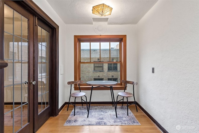 interior space with french doors, light hardwood / wood-style floors, and a textured ceiling