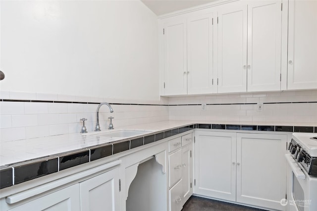 kitchen featuring backsplash, white cabinetry, white gas stove, and sink