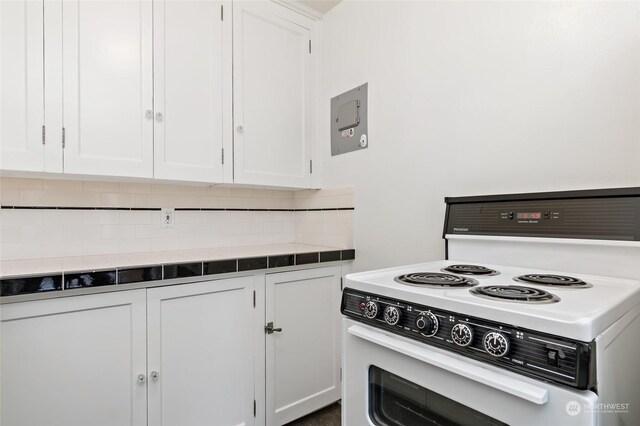 kitchen with white cabinets, backsplash, and white range with electric stovetop