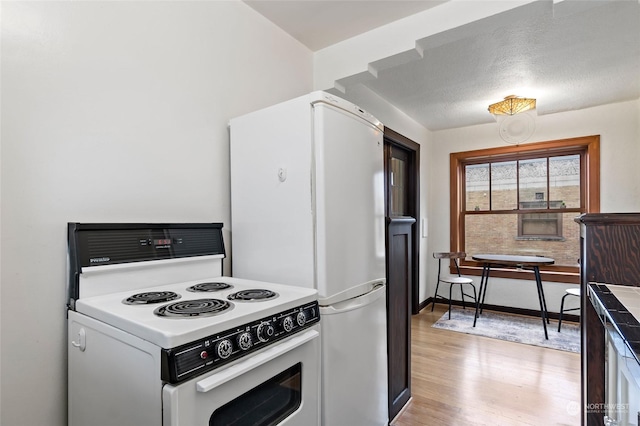 kitchen featuring a textured ceiling, white appliances, and light hardwood / wood-style floors