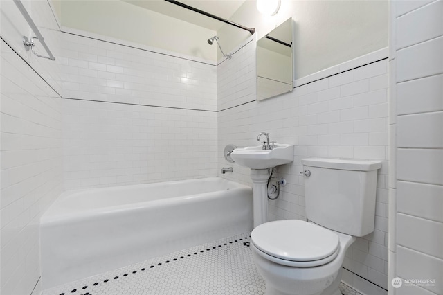 bathroom featuring tiled shower / bath, tile walls, and toilet