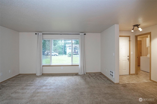 carpeted empty room with washer / clothes dryer and a textured ceiling