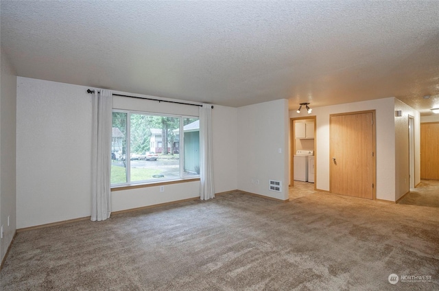 carpeted empty room featuring washer / clothes dryer and a textured ceiling