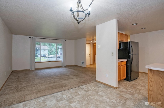 kitchen featuring light carpet, a textured ceiling, a chandelier, and black fridge