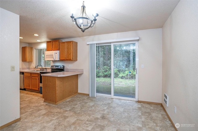 kitchen with pendant lighting, sink, appliances with stainless steel finishes, a notable chandelier, and kitchen peninsula