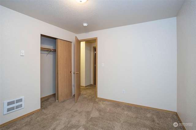 unfurnished bedroom with a textured ceiling, light colored carpet, and a closet