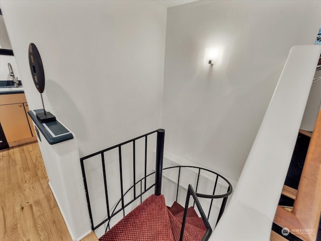 staircase with hardwood / wood-style floors and sink