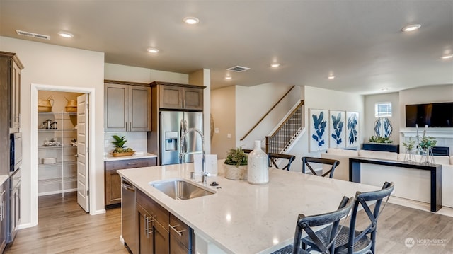 kitchen with a large island, sink, light stone countertops, a kitchen bar, and appliances with stainless steel finishes