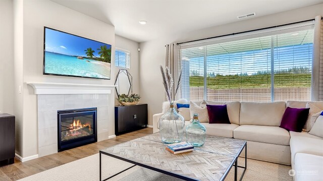 living room with light hardwood / wood-style floors and a tiled fireplace