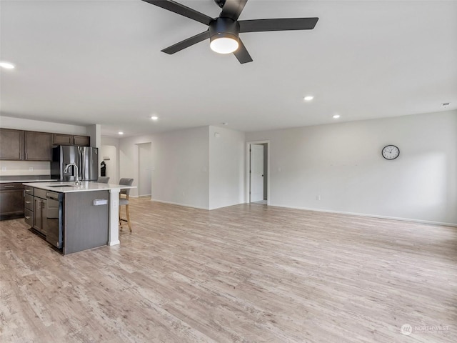 kitchen featuring a kitchen bar, sink, dishwasher, light hardwood / wood-style floors, and an island with sink