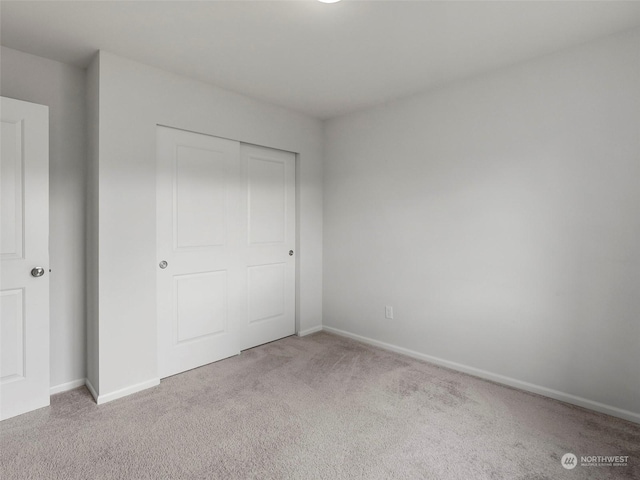 unfurnished bedroom with light colored carpet and a closet